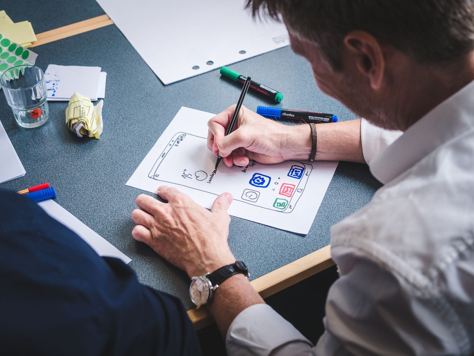 Designer sketching a mobile app screen on paper