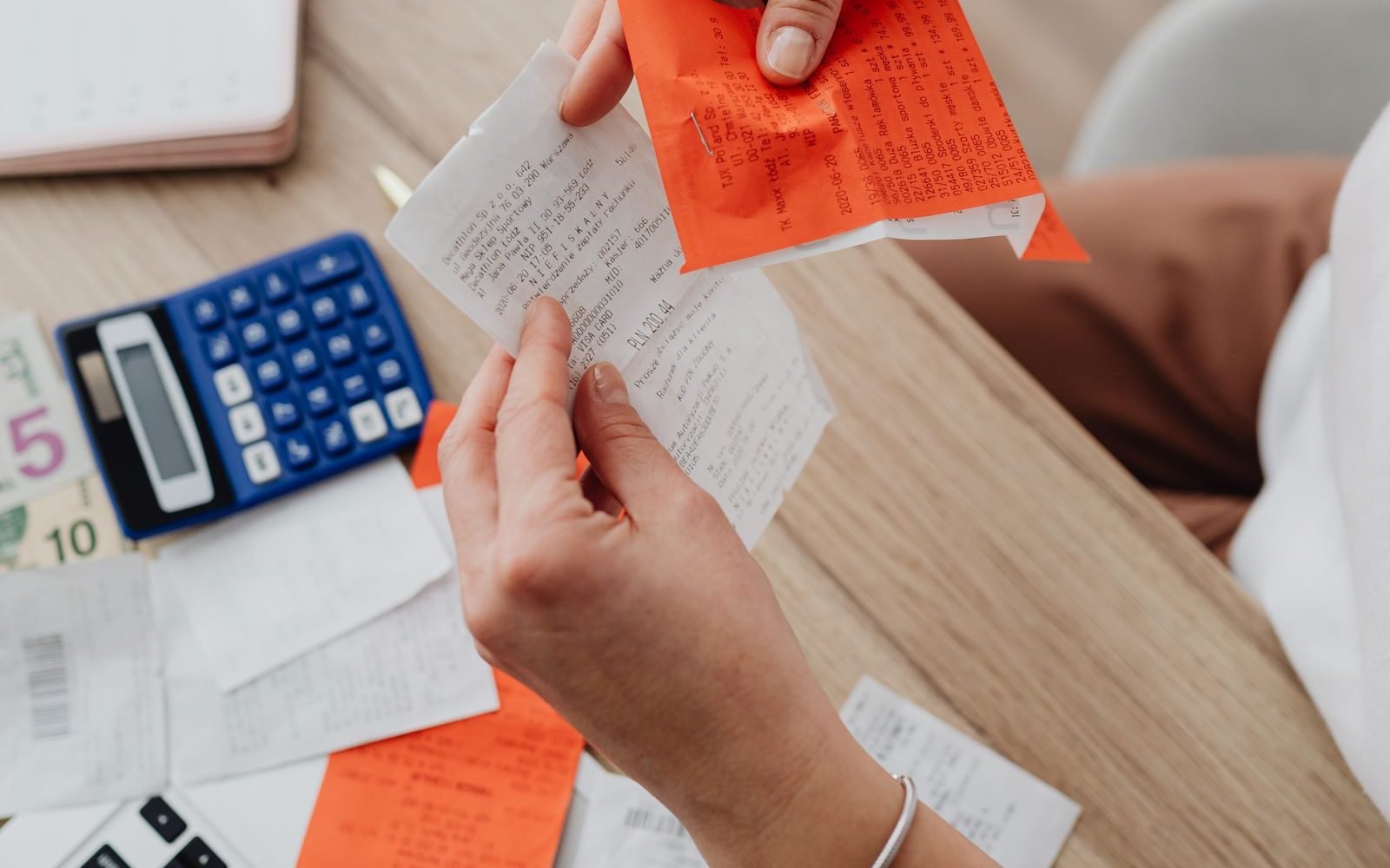 Hands sorting paper receipts beside a calculator