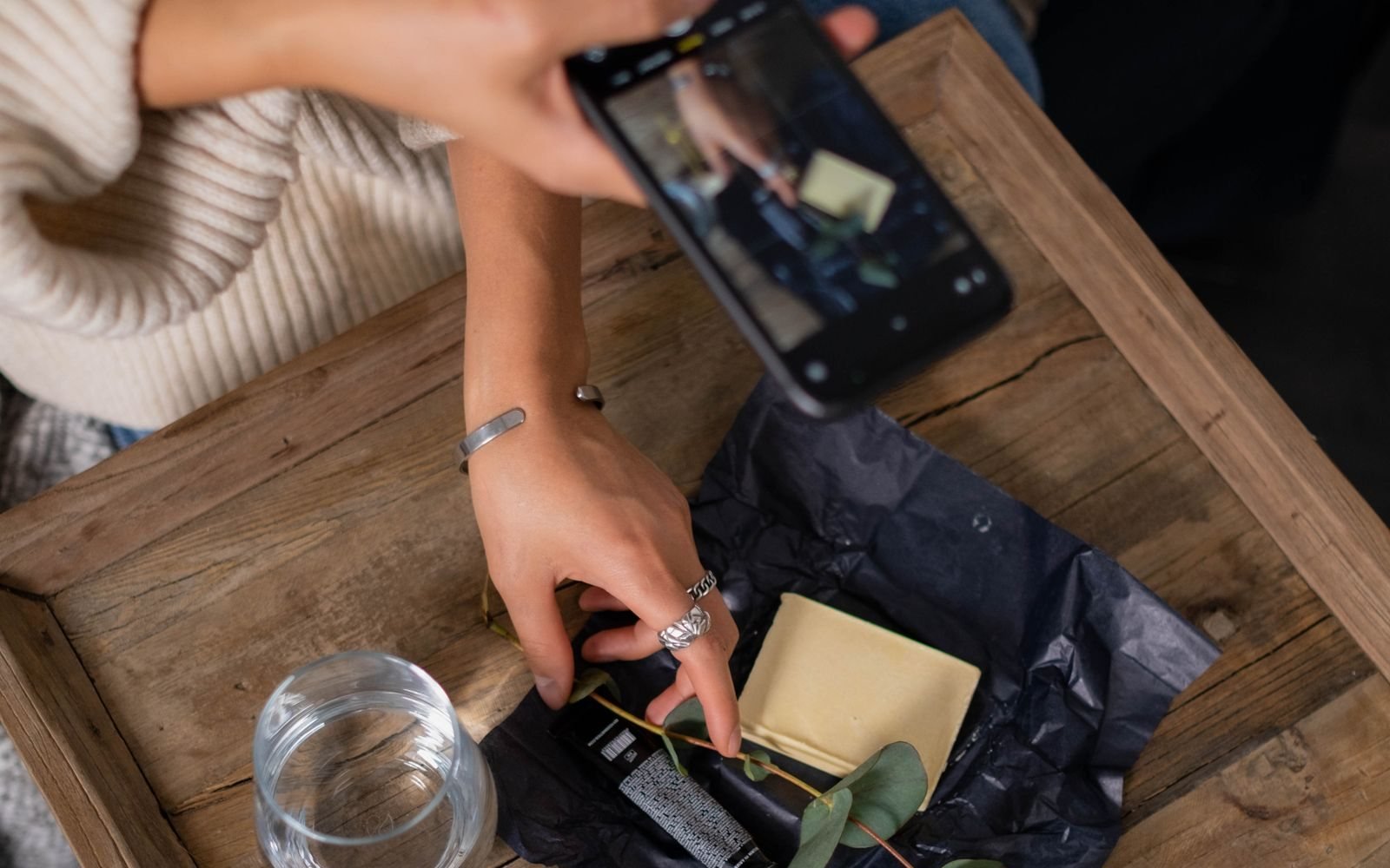Seller photographing a skincare product on a tray with her phone
