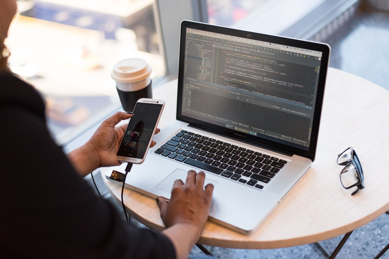 Developer testing an Android app on a phone connected to a laptop